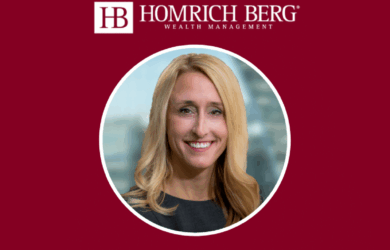 A woman with long blonde hair is smiling. She is wearing a black top. The background is maroon with the text Homrich Berg Wealth Management and a logo above the image.