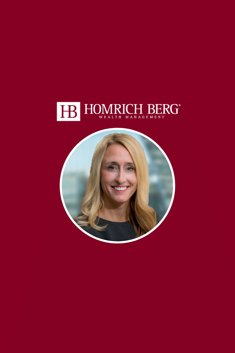 A woman with long blonde hair is smiling. She is wearing a black top. The background is maroon with the text Homrich Berg Wealth Management and a logo above the image.