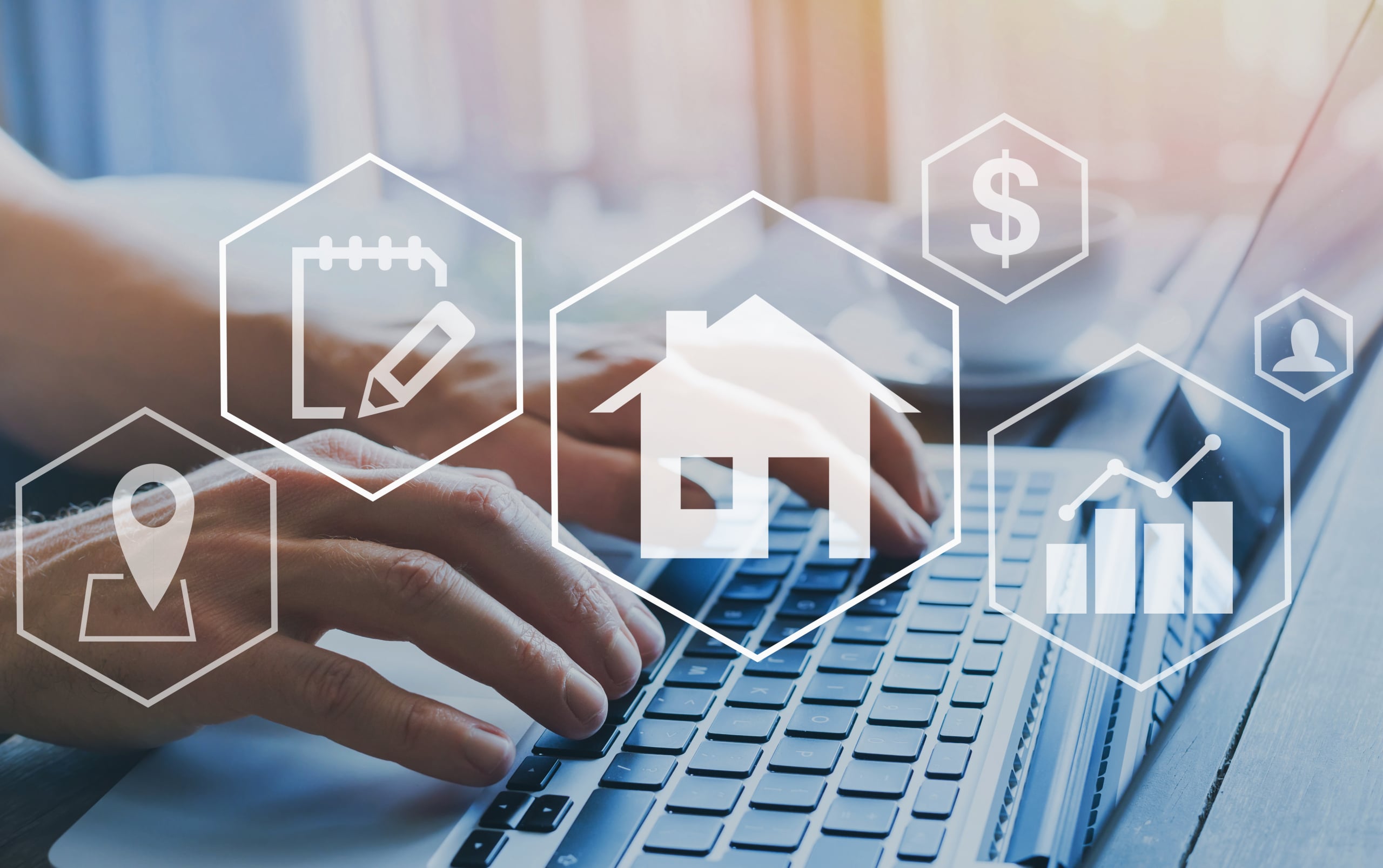 Hands typing on a laptop keyboard with transparent hexagons overlayed. Icons within hexagons depict a house, pencil and notebook, location pin, dollar sign, person, and a bar chart with an upward trend. Soft sunlight filters in the background.