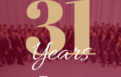 A large group of people stand together smiling in front of a backdrop displaying 31 Years in large letters. At the bottom, Homrich Berg Wealth Management is written with the companys logo.
