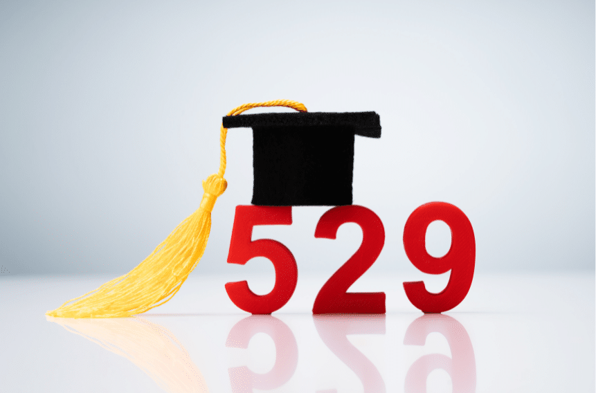 A small graduation cap with a yellow tassel sits atop the number 529 in bold red against a light background, representing a 529 college savings plan.