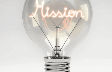 A clear light bulb with the word Mission glowing inside as the filament, set against a plain gray background.