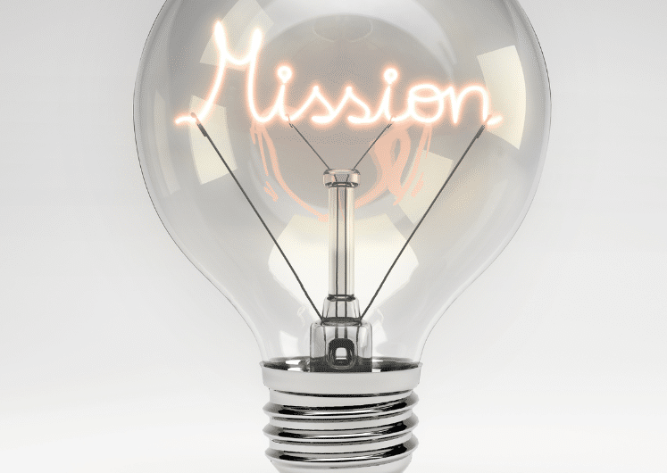 A clear light bulb with the word Mission glowing inside as the filament, set against a plain gray background.