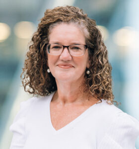 A woman with curly hair wearing glasses.