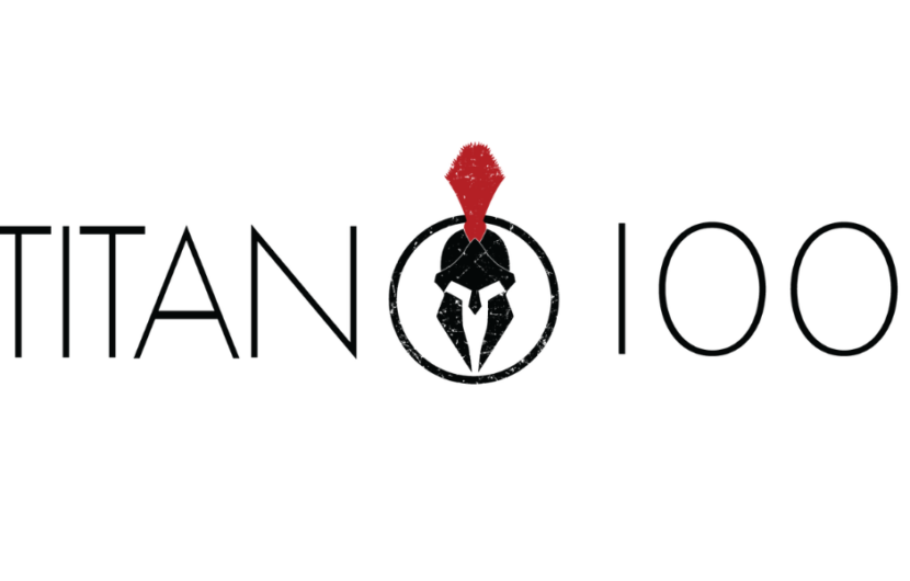 The image displays the text TITAN 100 in black with a stylized Spartan helmet in a black circle replacing the second O. The helmet has a red crest on top. The background is white.
