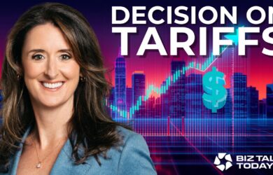 A smiling woman in a blue blazer stands in front of a city skyline with digital financial graphics. Large text reads Decision on Tariffs. The Biz Talk Today TV logo is in the bottom right corner.