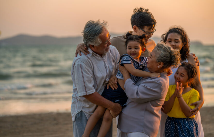 A group of people holding a child on a beach.