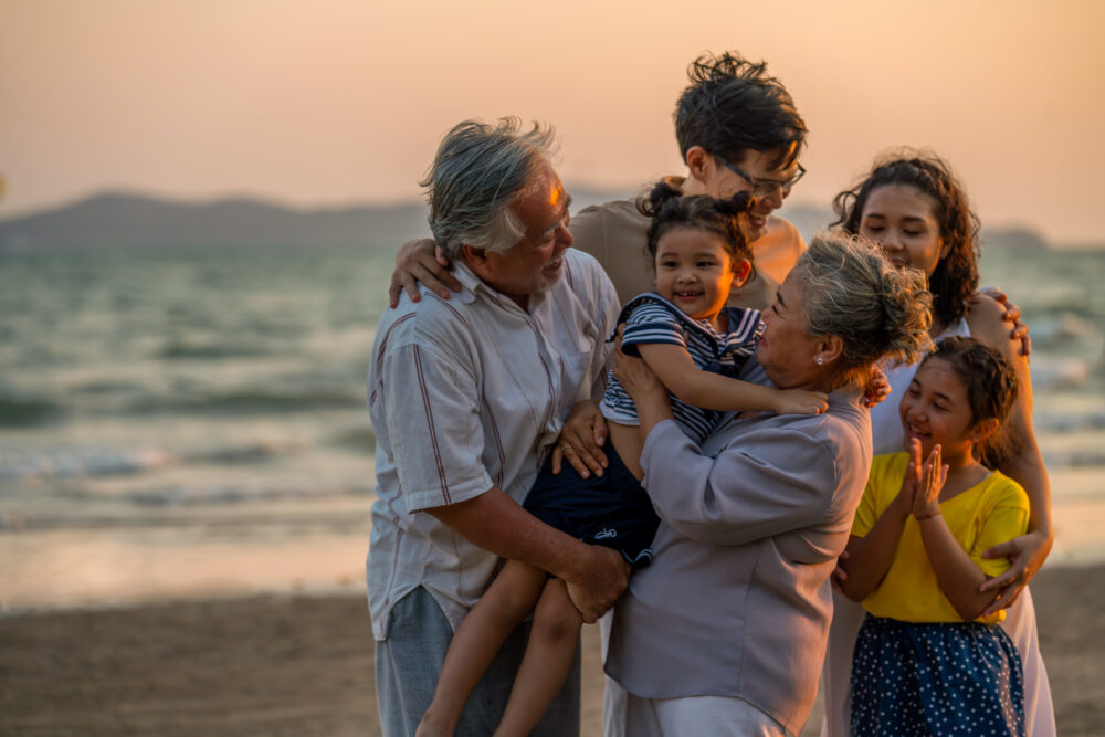 A group of people holding a child on a beach.