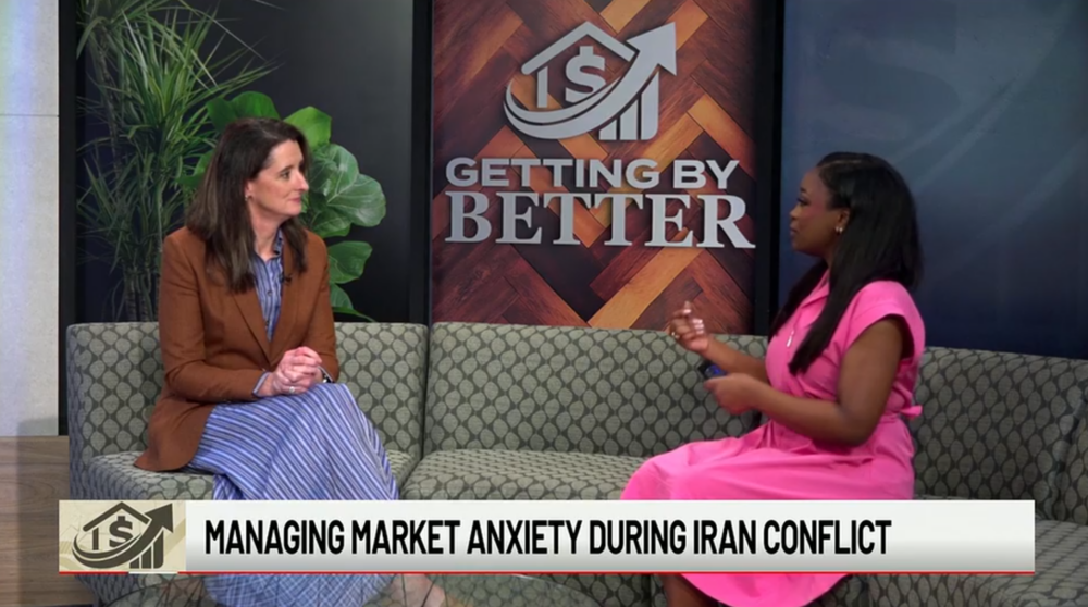 Two women sit on a couch in a TV studio, engaged in conversation. A sign behind them reads GETTING BY BETTER. The news ticker below says, Managing market anxiety during Iran conflict.