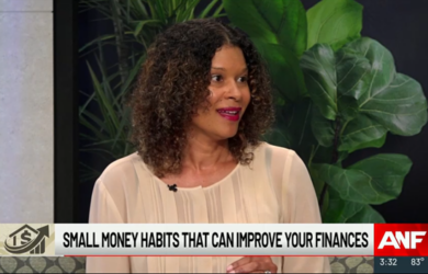 A woman with curly hair and a light blouse speaks on a TV show. The screen displays the text Small money habits that can improve your finances along with the ANF logo and the time and temperature at the bottom. Lush green plants are in the background.