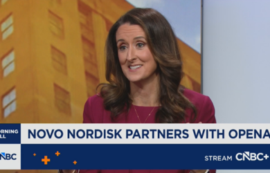 A woman with long brown hair wearing a burgundy blazer speaks on a CNBC news segment. The headline reads, Novo Nordisk partners with OpenAI. The CNBC+ logo appears at the bottom right.