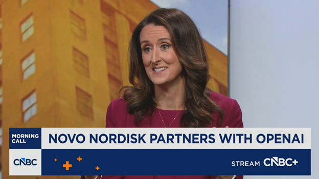 A woman with long brown hair wearing a burgundy blazer speaks on a CNBC news segment. The headline reads, Novo Nordisk partners with OpenAI. The CNBC+ logo appears at the bottom right.