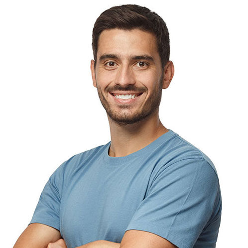 A man with short dark hair and a beard is smiling and standing with his arms crossed, wearing a light blue t-shirt against a plain white background.